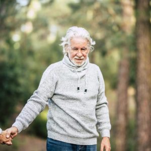 Assistance and disease alzheimer problems for old people- senior man holding hands and walk in the forest to enjoy the outdoor nature leisure activity